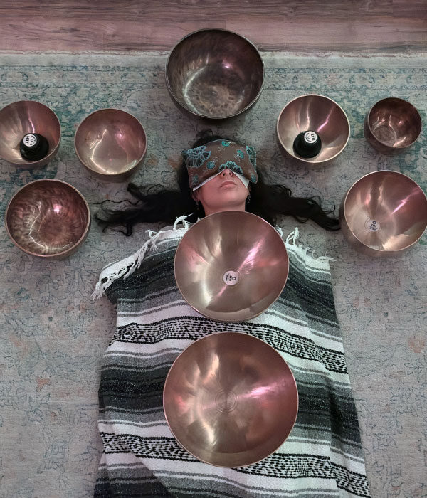 woman lying on the floor with hinalayan bowls surrounding her head and on her body at GlassWing Medicine in Onalaska WA