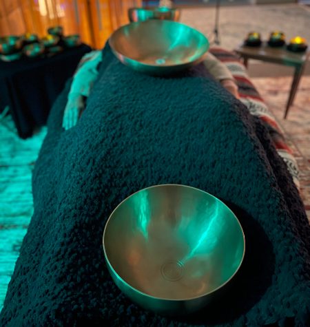 Woman lying on a massage table with Himalayan bowls for sound therapy